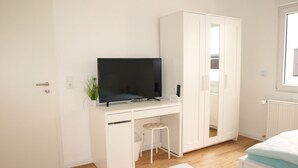 A bedroom with a bed, a white wardrobe, a desk with a television, and a window. - Nice apartment centrally located in the Rhine-Main area (Schöneck)