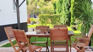 An outdoor patio with a covered table and chairs, surrounded by a garden and a view of a residential area. - Nice apartment centrally located in the Rhine-Main area (Schöneck)