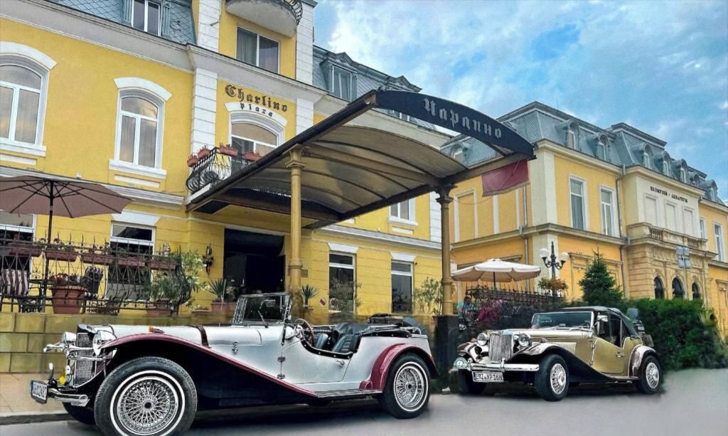 A vintage car parked in front of a yellow building with a sign that reads 'Carlin Plaza.'