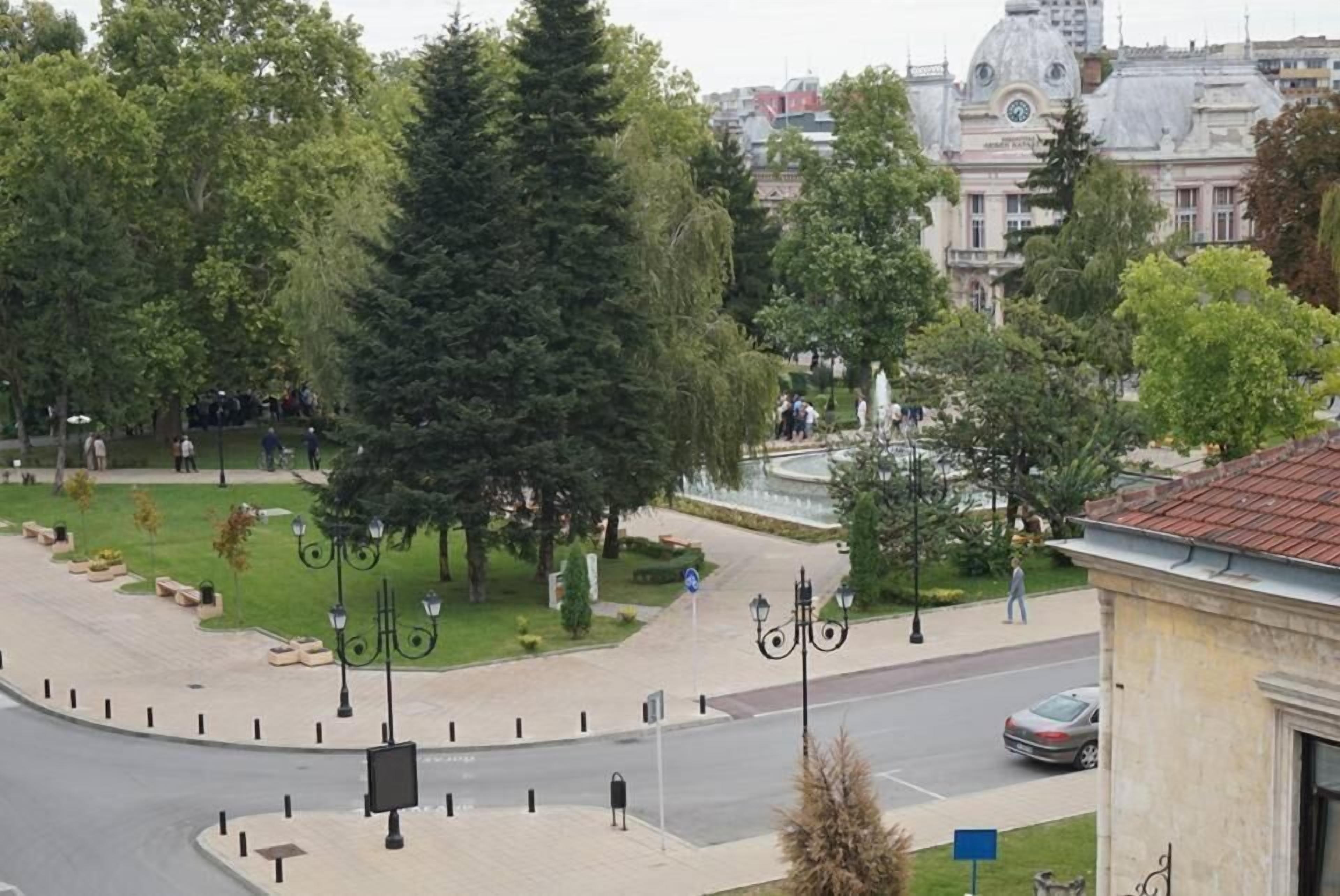 A park with a roundabout, trees, and a building in the background.