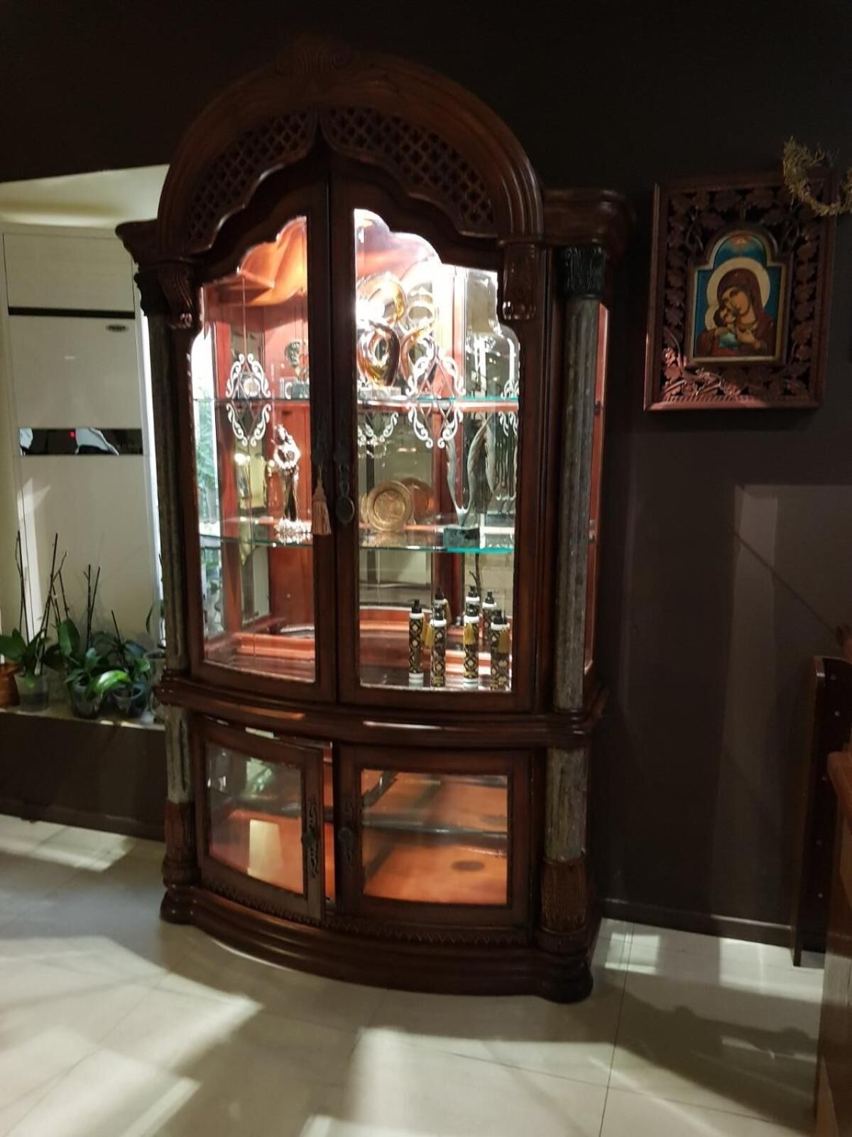 A wooden display cabinet with glass doors, containing various items.