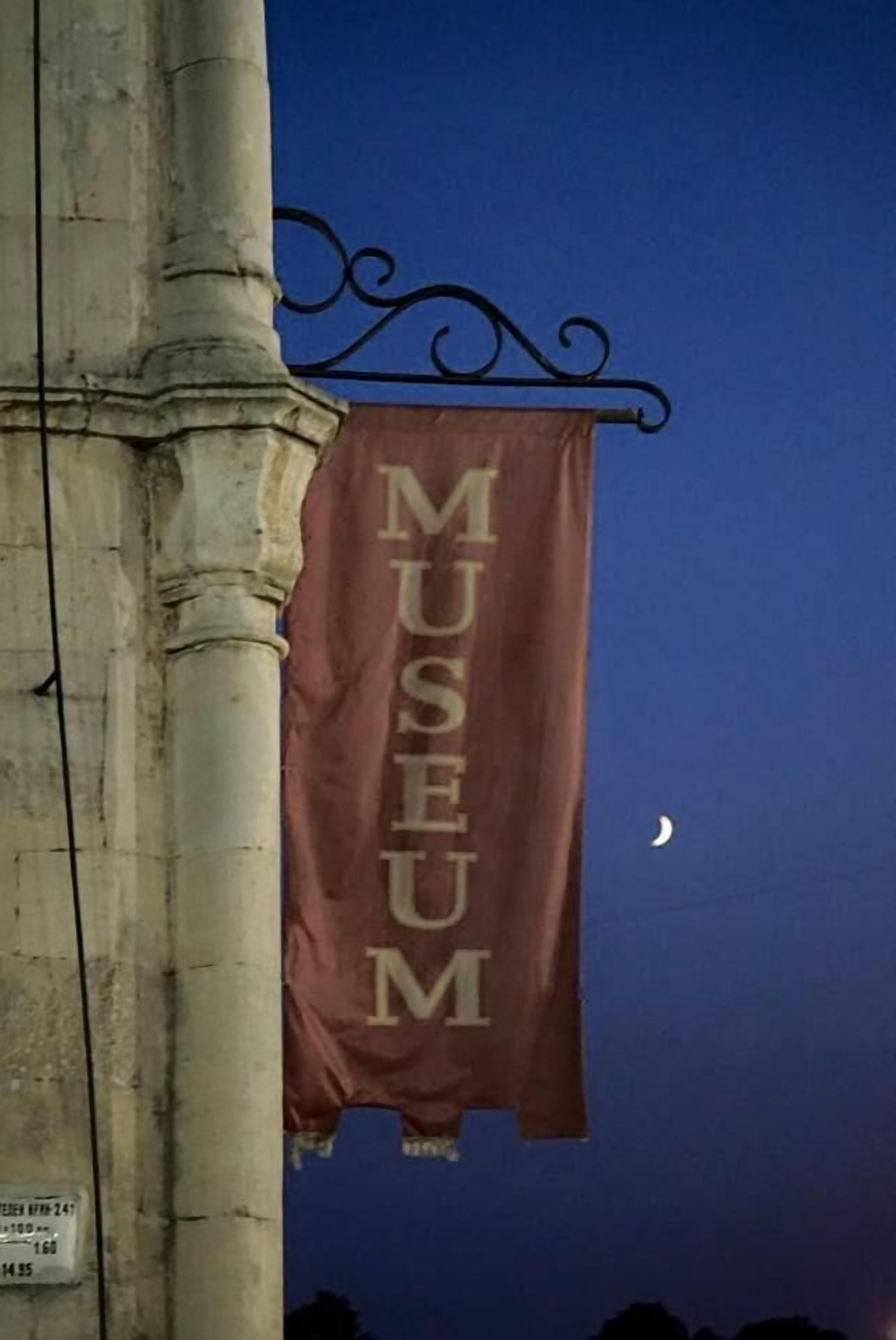 Une banderole est suspendue à une structure métallique et porte l’inscription « MUSÉE ».