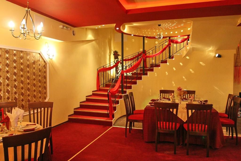 Un comedor con alfombra roja, una escalera con barandillas rojas y un candelabro.