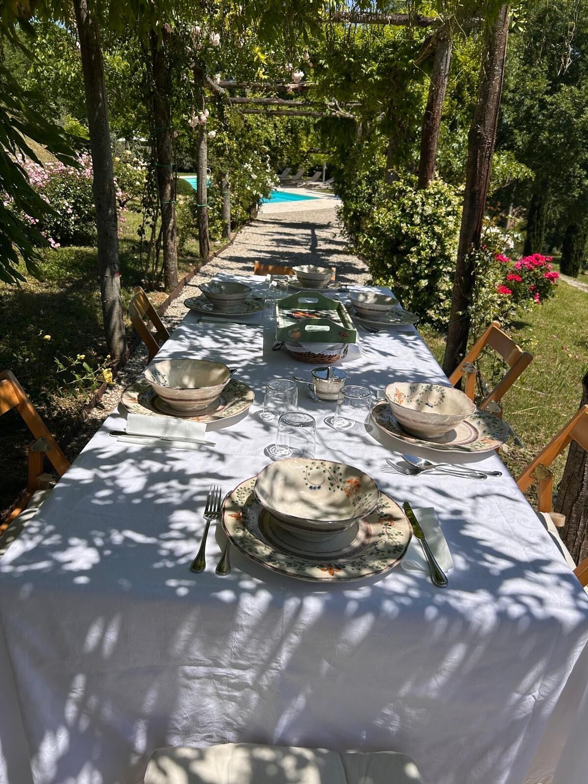 Une table dressée pour un repas en plein air, avec une piscine en arrière-plan.