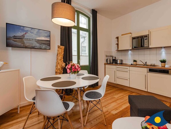Une cuisine moderne avec des meubles blancs, un four encastré et un four à micro-ondes.