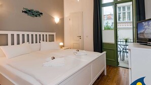 Habitación de hotel con cama, televisor, puerta y vista al exterior.