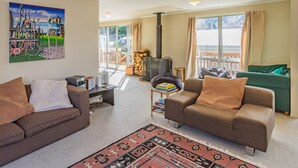 Un salon comprenant deux canapés, une table basse, une cheminée et une grande fenêtre donnant sur une terrasse.