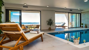 Een zwembadgedeelte met ligbedden en uitzicht op zee.