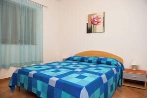 Ein Schlafzimmer mit kariertem Bettbezug, einem Holzkopfbrett, einem Nachttisch mit Lampe und einem Bild an der Wand.