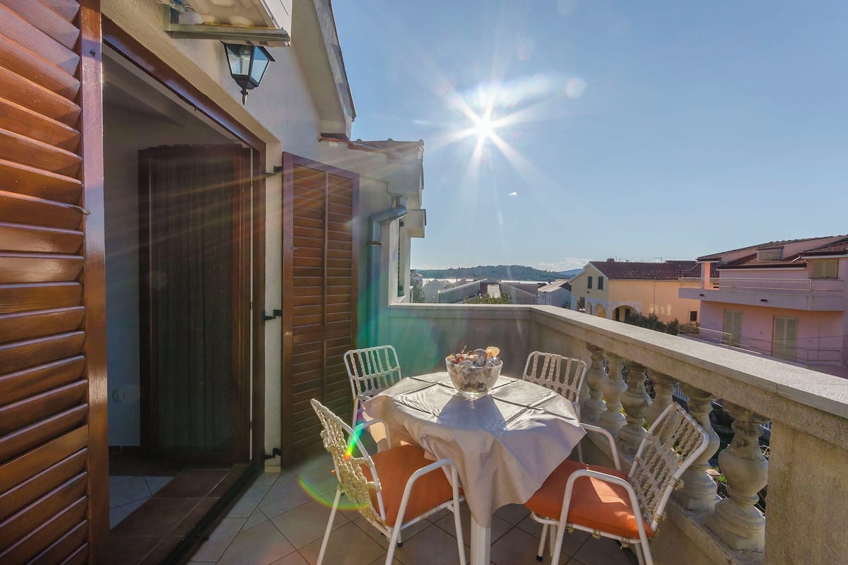 A balcony with a table set for dining, overlooking a residential area.