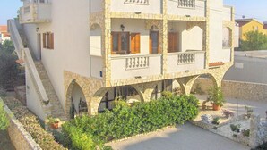 Un edificio de varios pisos con balcones, arcos de piedra y una escalera que conduce a la entrada.