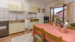 Cocina compacta con comedor, refrigerador, estufa y mesa lista para dos personas, con una botella de champán.