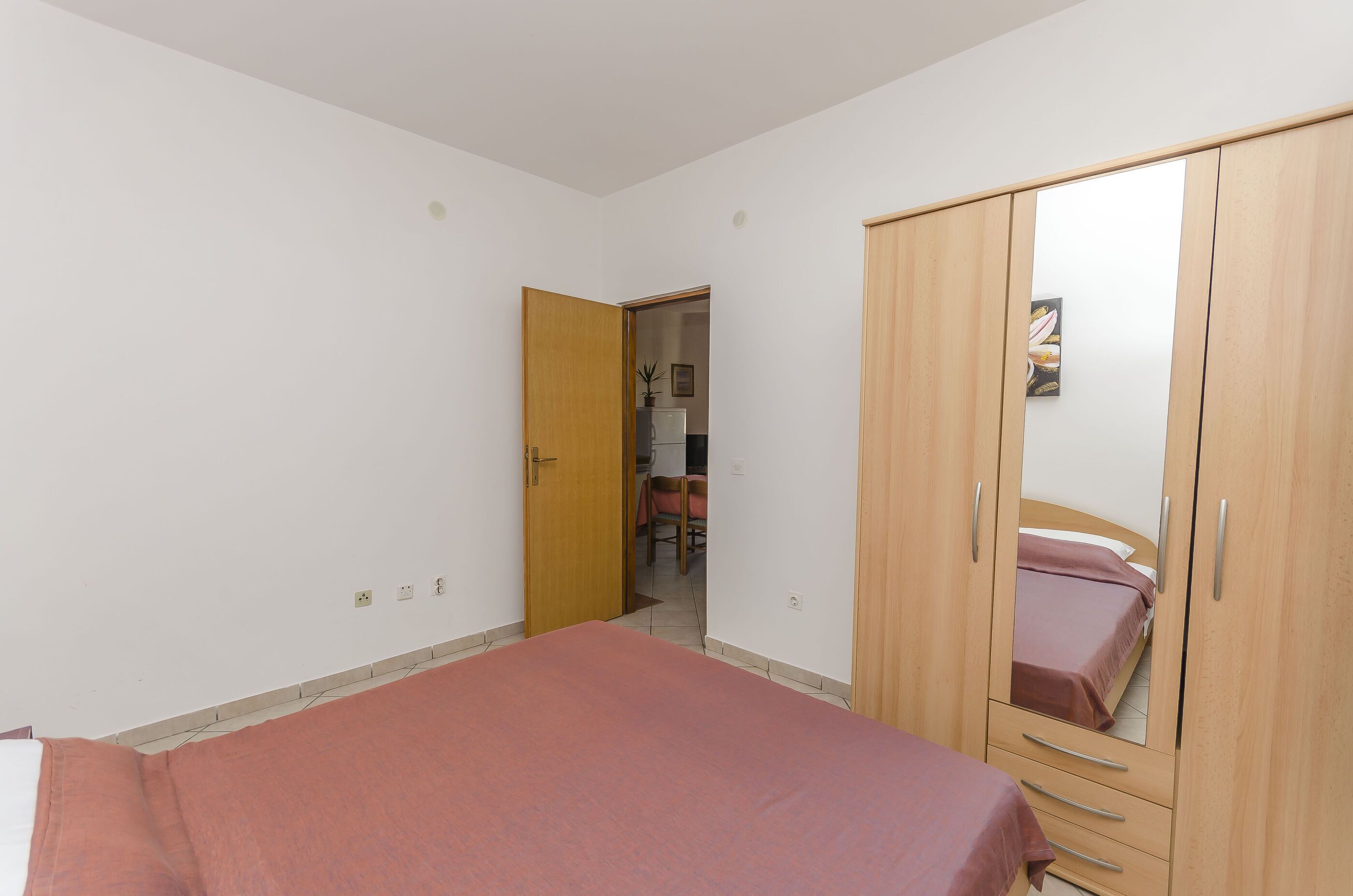 Ein Schlafzimmer mit einem Bett, einem Holzschrank und einer Tür zu einem Badezimmer.