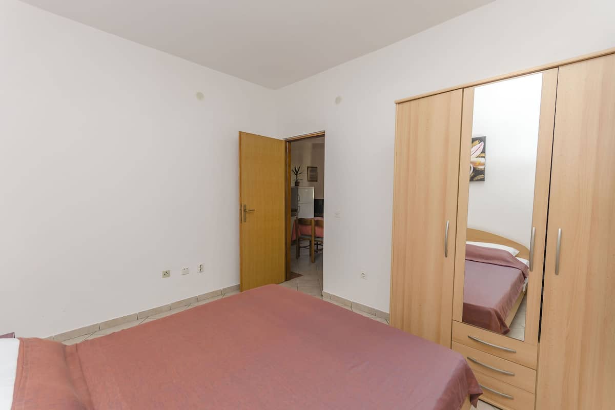 A bedroom with a bed, wooden wardrobe, and a door leading to a bathroom.