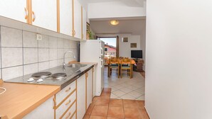 Una cocina con estufa, pileta y armarios, que da a un comedor con mesa y sillas.