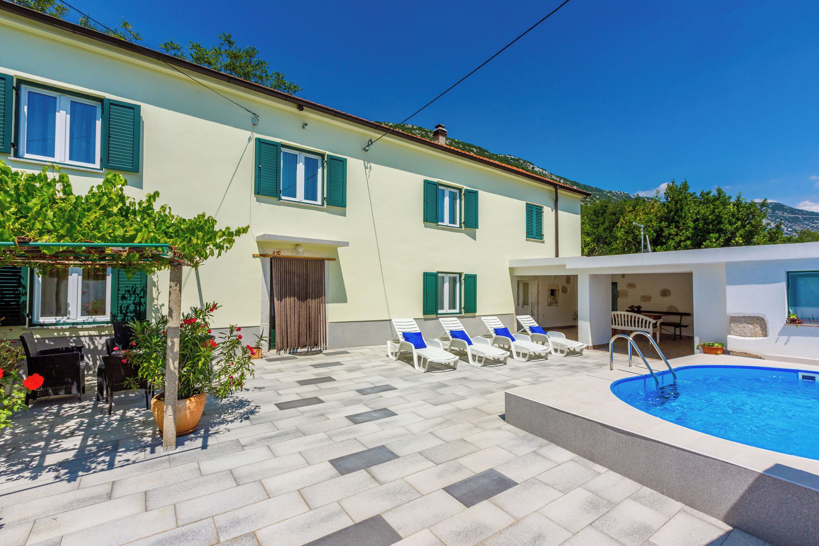A poolside area with a pool, lounge chairs, and a table with chairs.