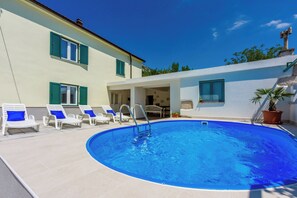 A swimming pool with lounge chairs, a covered patio, and a building with green shutters. - House Annie (Vinodol)
