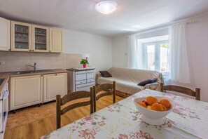 A compact kitchen with a sink, cabinets, and a dining area with a table and chairs. - House Annie (Vinodol)