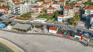 An aerial view of a coastal town with residential buildings, a beach, and a small commercial area. - Apartments Tily (Okrug Gornji)