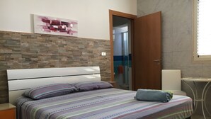 A bedroom with a bed, a bathroom door, and a small table.