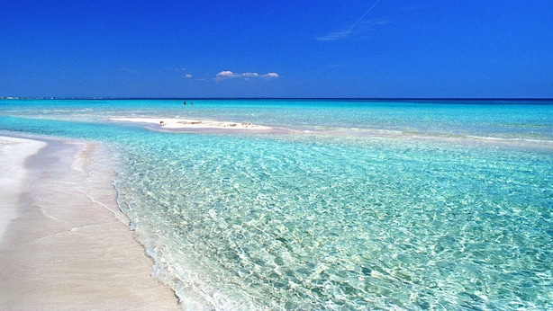 A beach with clear turquoise water and white sand.