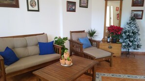 Una sala de estar con sofá, sillón, mesa de centro y plantas en macetas.