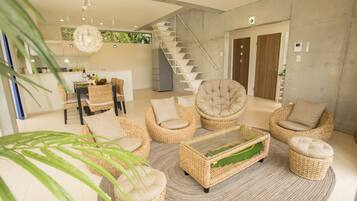 A modern interior with wicker furniture, a staircase, and a kitchen area.