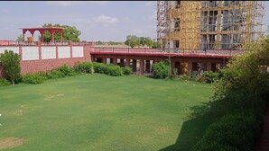 A building with a red roof and brick walls, surrounded by a well-maintained lawn and some greenery. - Rawat Resorts (Tivari)