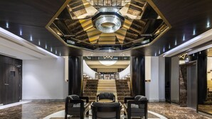 A lobby with a central seating area, a grand staircase, and a modern chandelier. - Hotel Sfax Palace by Plaza Hotels & Resorts (Sfax)