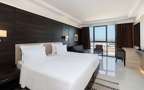 Une chambre d’hôtel moderne dotée d’un grand lit, d’un coin salon et d’une vue sur la ville.