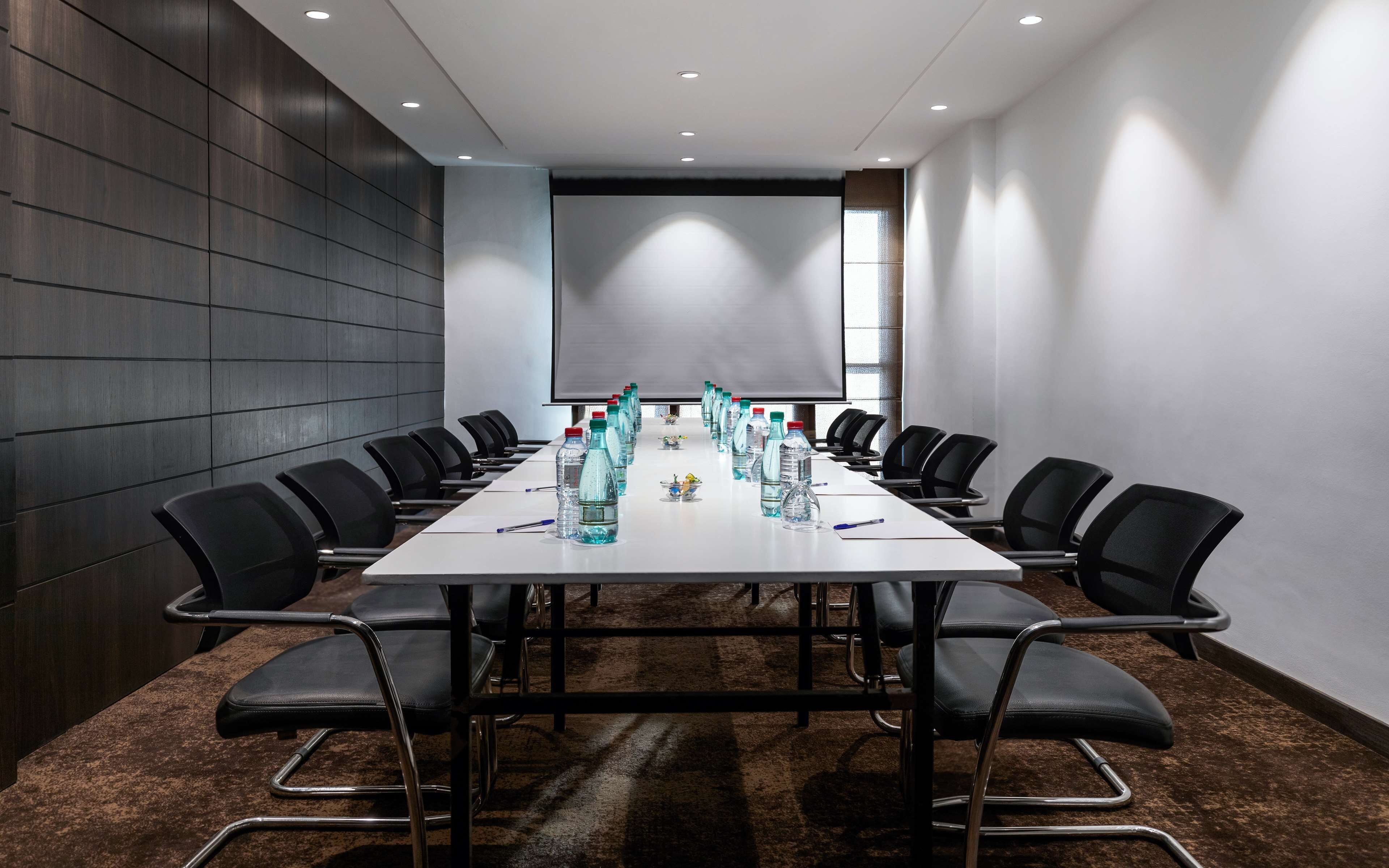 A conference room with a long table, black chairs, and water bottles.