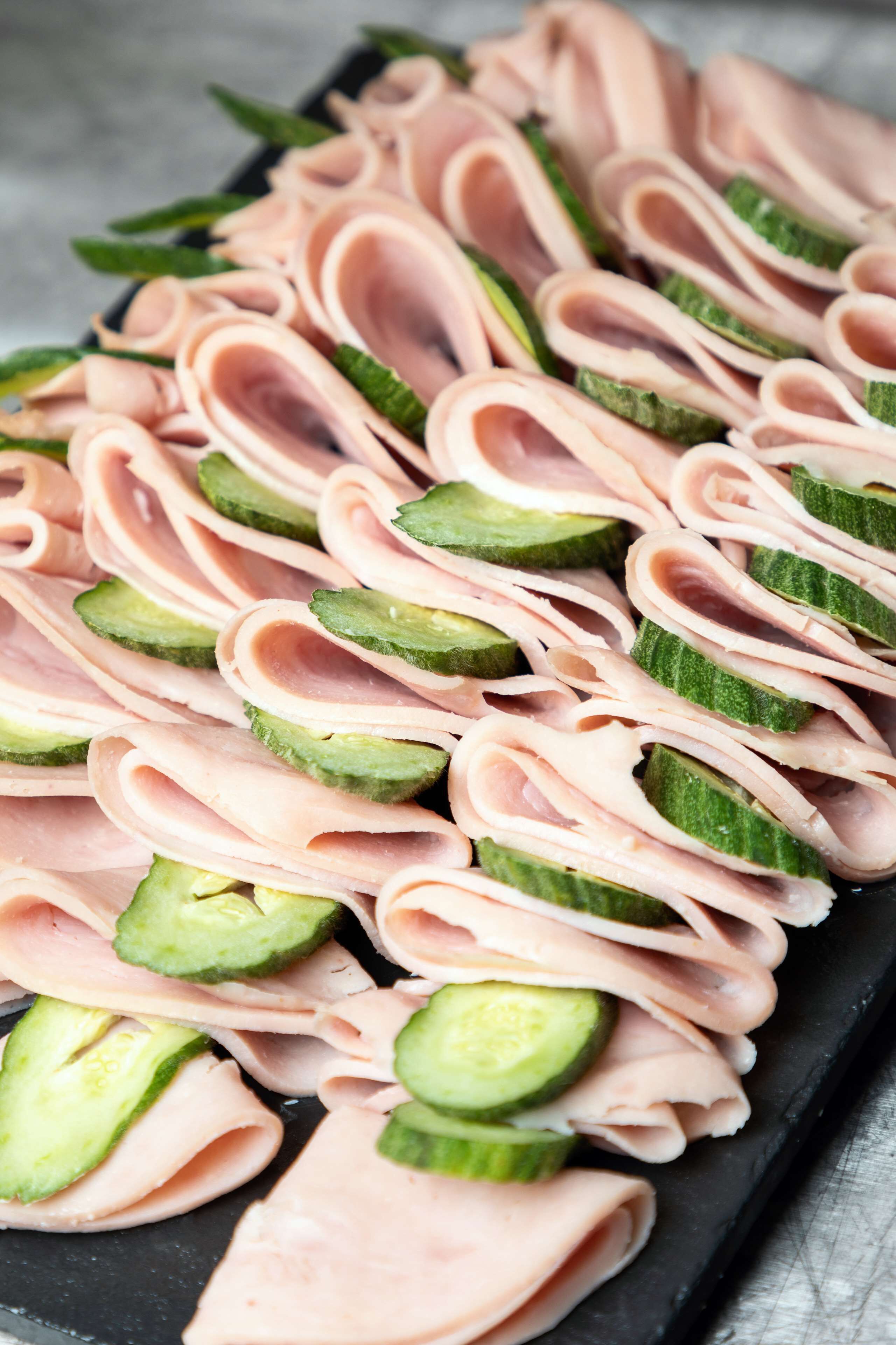 Una bandeja con lonchas de jamón y pepino, dispuestas cuidadosamente.