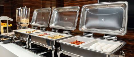 Una mesa de buffet con múltiples dispensadores de comida y una estación de bebidas.