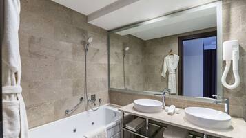 Un baño moderno con bañera, dos lavamanos, un espejo grande y un perchero para toallas.