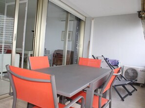 A conference room with a grey table and orange chairs, a sliding glass door, and a radiator on the wall. - Villeneuve-Loubet: Apartment with Terrace, Air Conditioning and Garage (Villeneuve-Loubet)