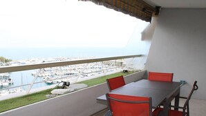 A balcony with a table and chairs, overlooking a marina with boats.