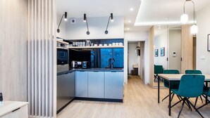 Cozinha moderna com ilha central, eletrodomésticos embutidos e área de refeições com cadeiras verdes.