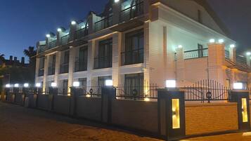 Un edificio de varios pisos con diseño moderno, con balcones y un acceso con portón.