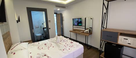 A hotel room with a bed, a desk, a television, and a minibar.