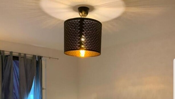 Una camera da letto con un letto, due comodini, una lampada, una coperta a quadretti e un lampadario.
