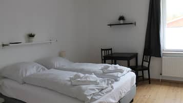 Una camera da letto con un letto, un comodino, una sedia e una finestra con tende.