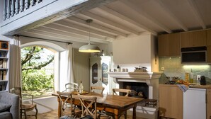 A cozy living room with a fireplace, wooden furniture, and a view of greenery outside. - L'Atelier, with its century-old oak trees and panoramic view of the Luberon region (Cucuron)