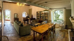 A cozy living room with a wooden dining table, a sofa, and a bookshelf. - L'Atelier, with its century-old oak trees and panoramic view of the Luberon region (Cucuron)