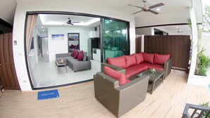 A modern living room with a red sofa, grey sofa, and a wicker coffee table. - The Elegance Pool Villas at KP Beach (Ko Chang)