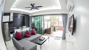A modern living room with a grey sofa, a coffee table, and a flat-screen TV mounted on the wall. - The Elegance Pool Villas at KP Beach (Ko Chang)