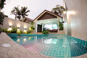 A swimming pool with a tiled deck, a covered patio area, and a view of a building with a sloped roof. - The Elegance Pool Villas at KP Beach (Ko Chang)