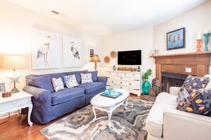 A living room with a blue sofa, white coffee table, and a fireplace.