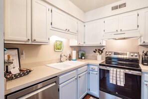 A kitchen with white cabinets, a stainless steel stove, and a sink.