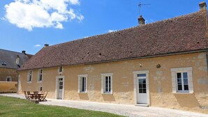 A two-story building with a tiled roof and a small garden area in front.