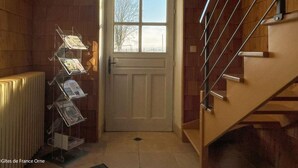A staircase with metal railings leading to a landing. A door with a window is visible, and a brochure stand is placed against the wall.